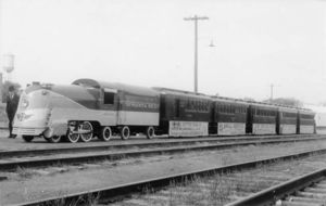 © Photo: Lucius Beebe A scale replica of Locomotive #3460 and the Chief sits trackside at Stillwater, Oklahoma on Armistice Day, 1939. The sides of the cars are adorned with banners touting the many benefits of travelling to California on the Santa Fe.